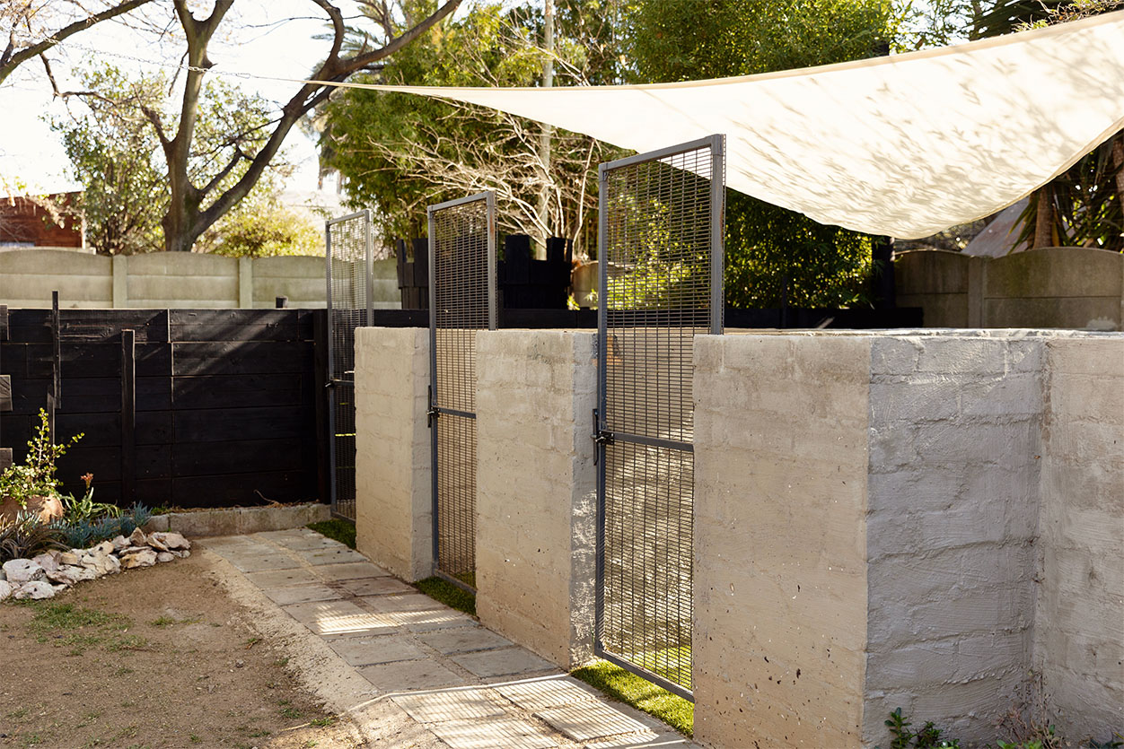Secure outdoor dog boarding runs protected by a large shade sail at The Robin House boutique dog hotel in Johannesburg.