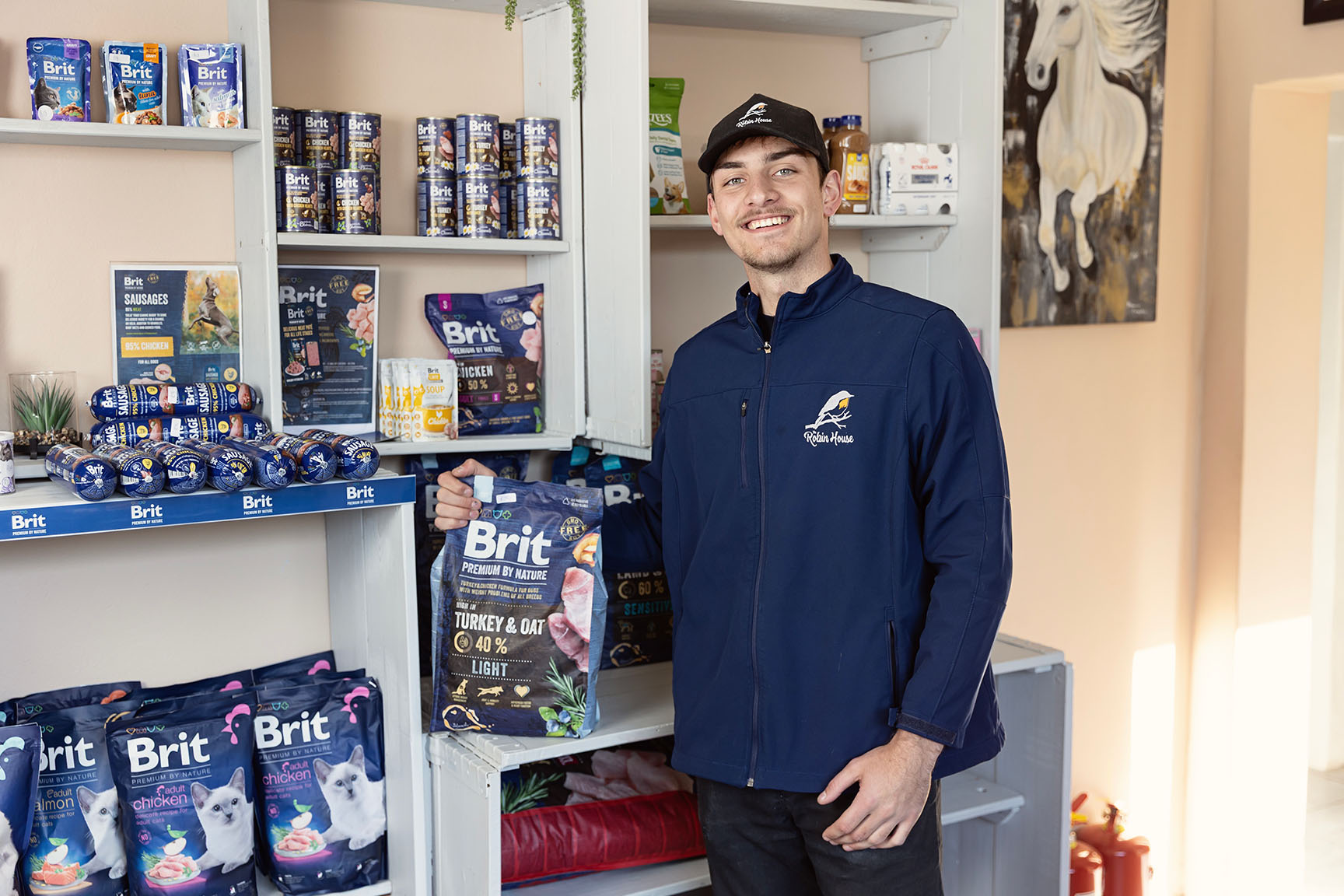 A friendly staff member at The Robin House vet shop in Johannesburg holding a bag of Brit Premium dog food.